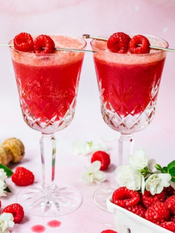 Front view of two raspberry mimosas garnished with raspberries.