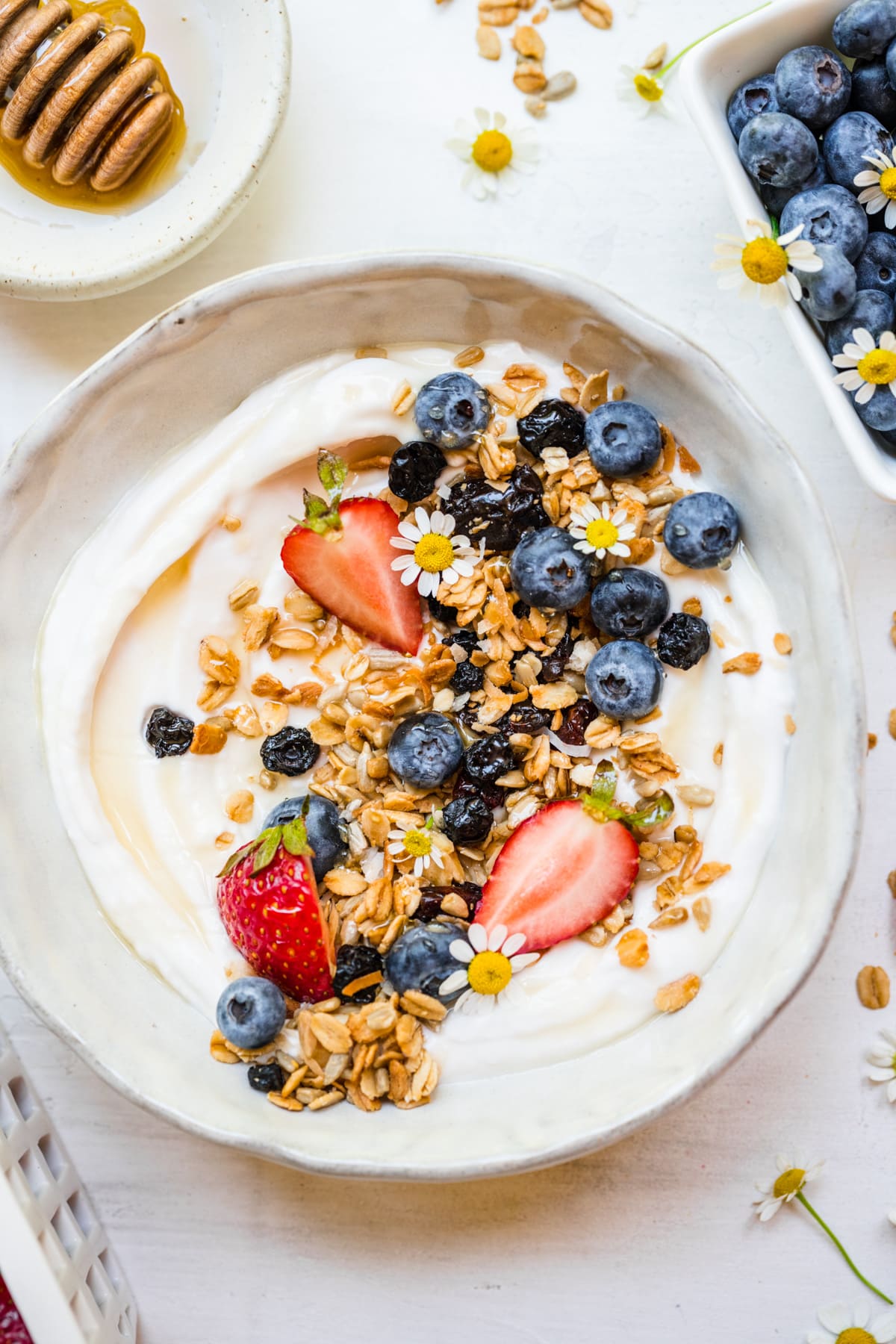 Overhead of finished berry granola in white bowl on top of yogurt.