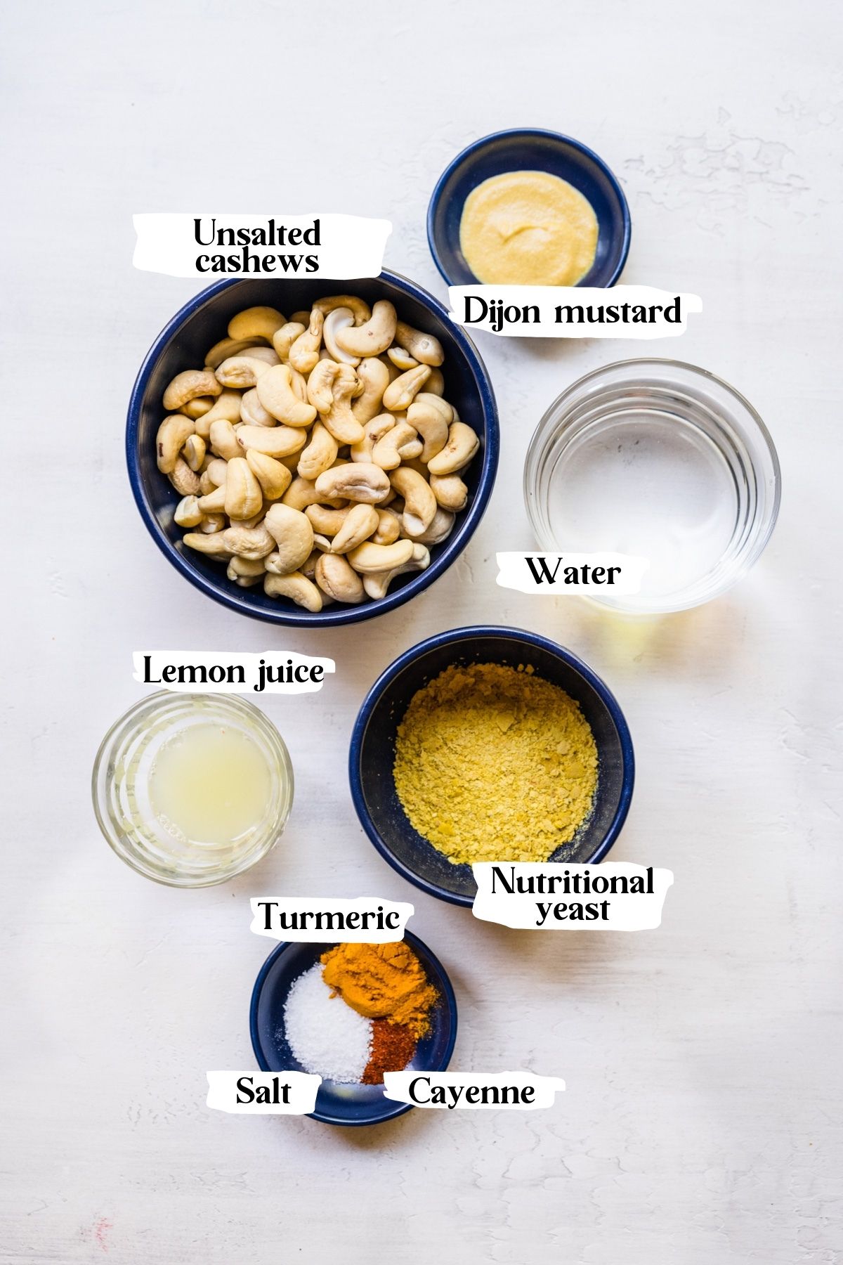 Overhead of vegan hollandaise ingredients including nutritional yeast, dijon mustard and cashews.