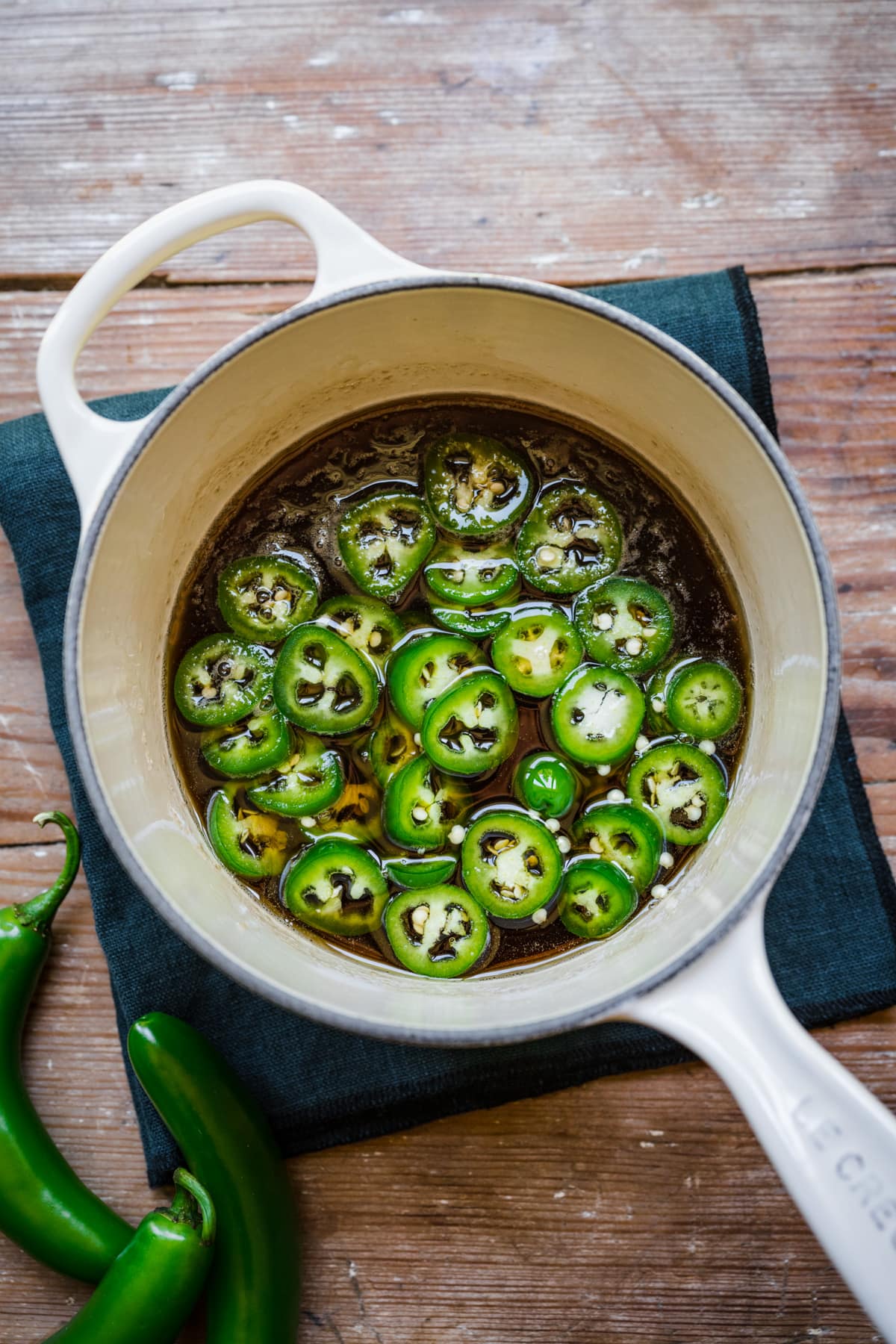 Overhead view of jalapeno simple syrup in a white saucepan.