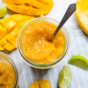 Finished mango jam in jar with spoon in it.