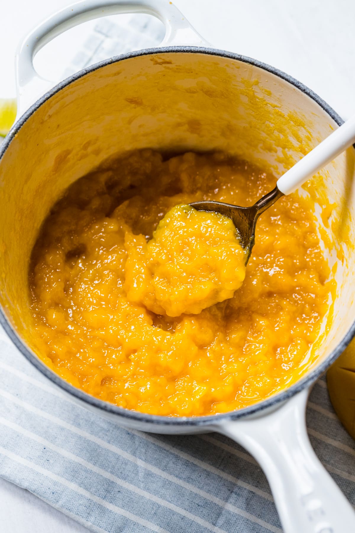 Close up view of mango jam in a white pot.