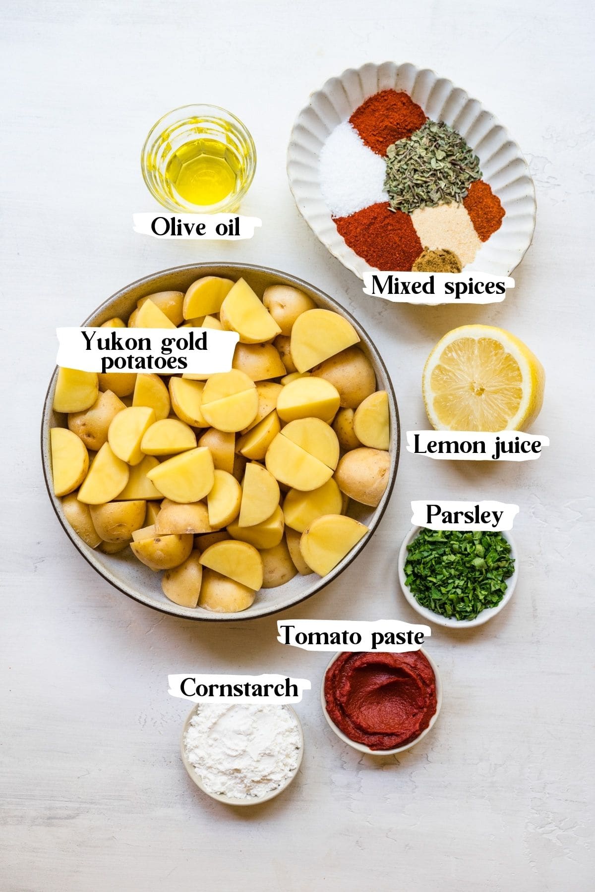 Overhead of the Spanish potato ingredients including yukon gold potatoes, tomato paste and parsley.