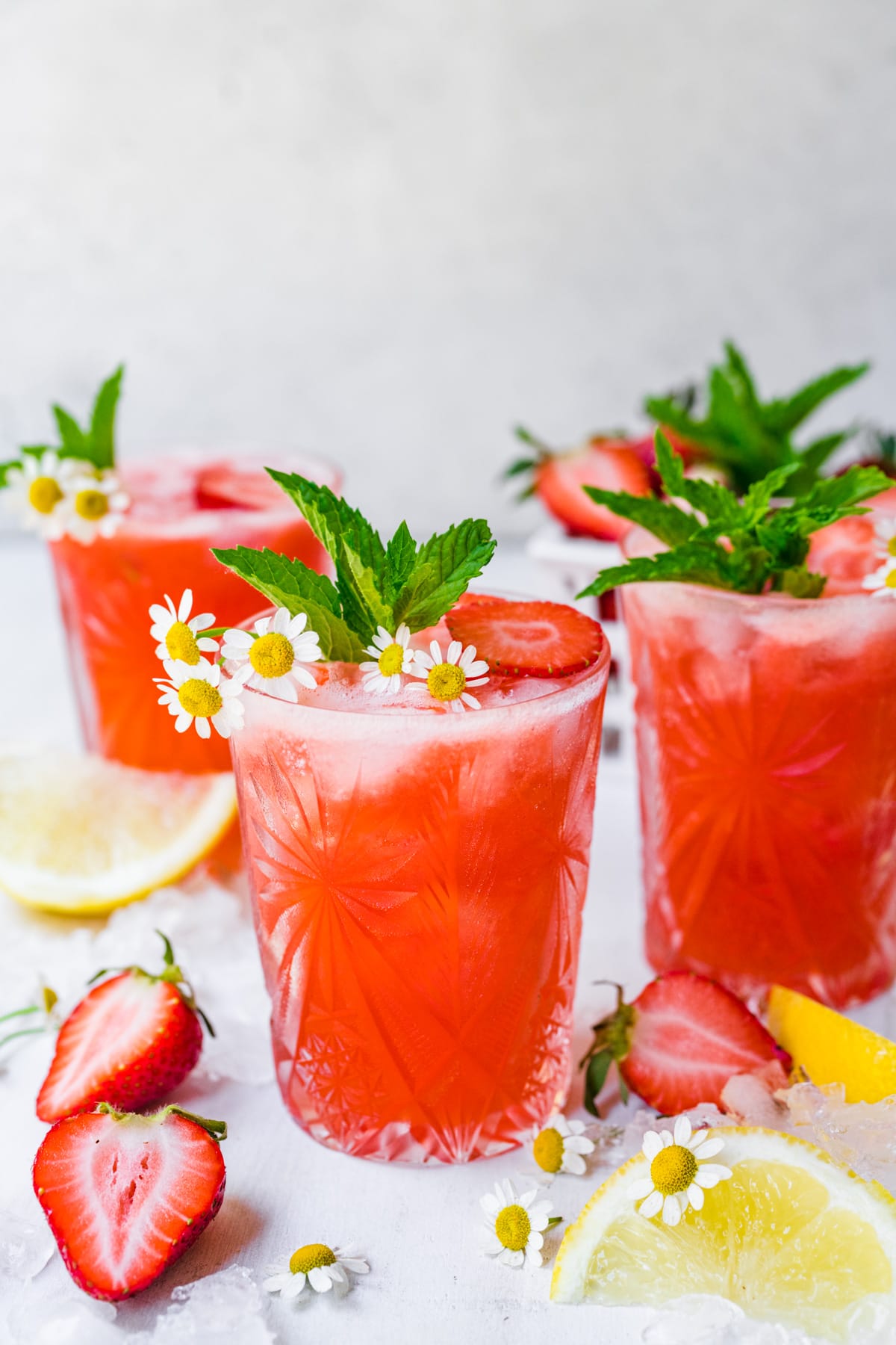 The finished strawberry mocktails with mint and floral garnish.