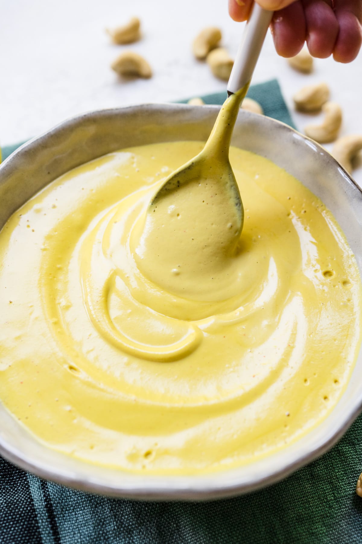 Close up of spoon in a bowl of hollandaise sauce.
