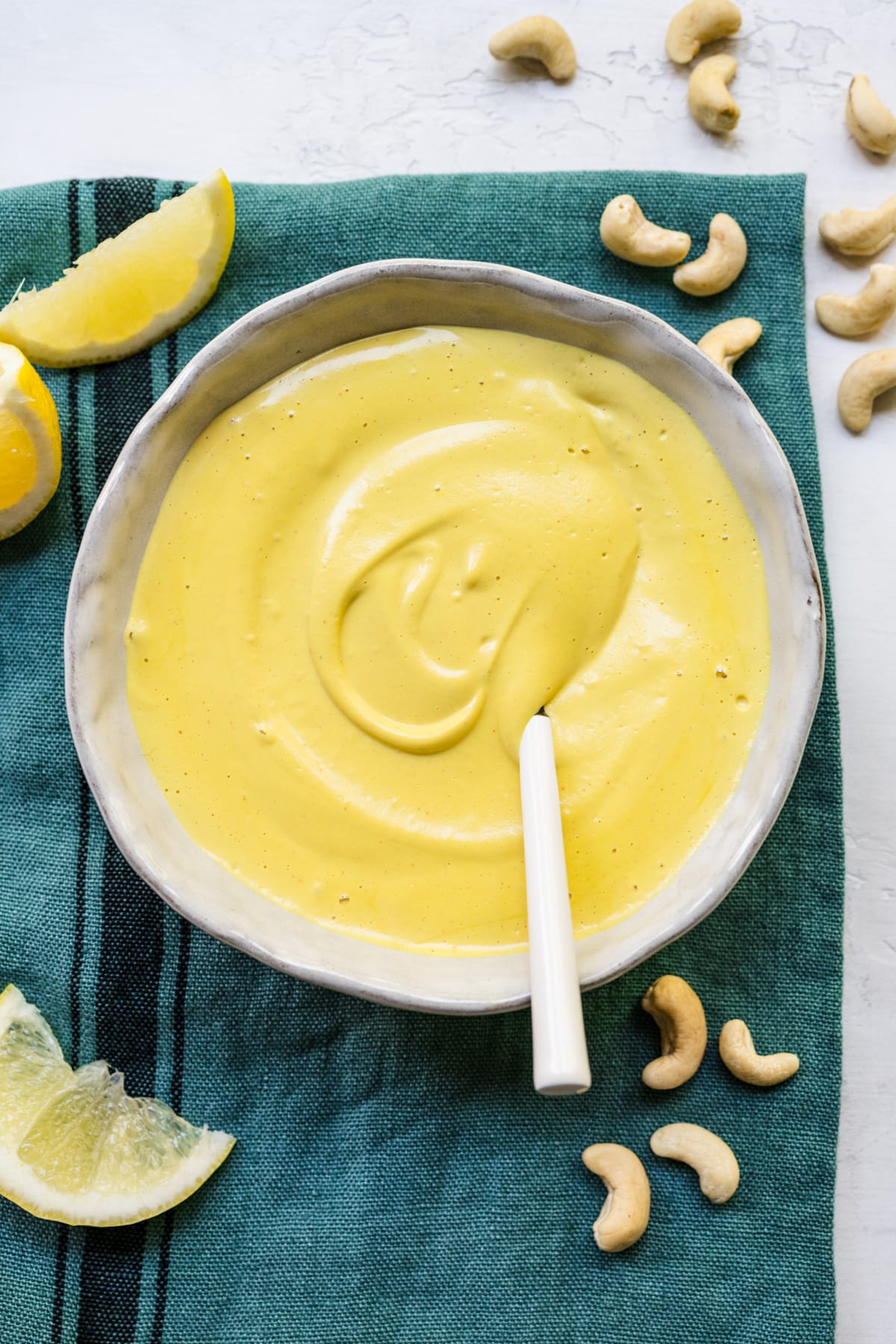 Finished hollandaise sauce in white bowl on blue cloth.