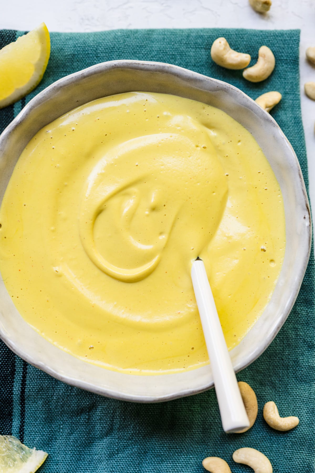 Close up view of vegan hollandaise sauce in a white bowl.