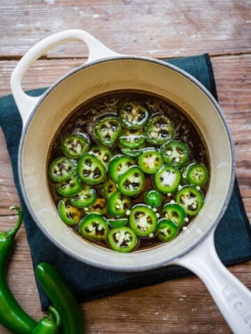 Overhead view of jalapeno simple syrup in a white saucepan.