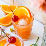Front view of amaretto stone sour garnished with a cherry and orange.