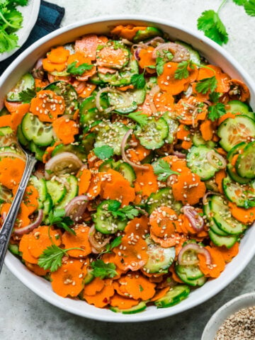 overhead view of carrot cucumber salad in white bowl.