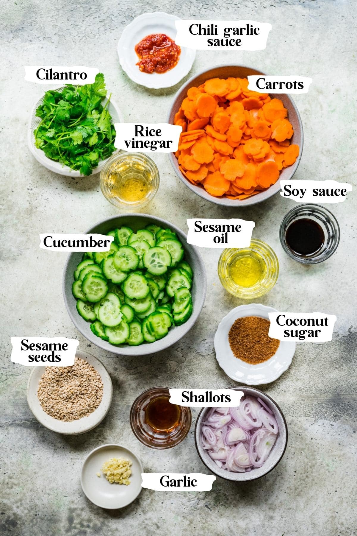 overhead view of ingredients for carrot cucumber salad in small prep bowls. 