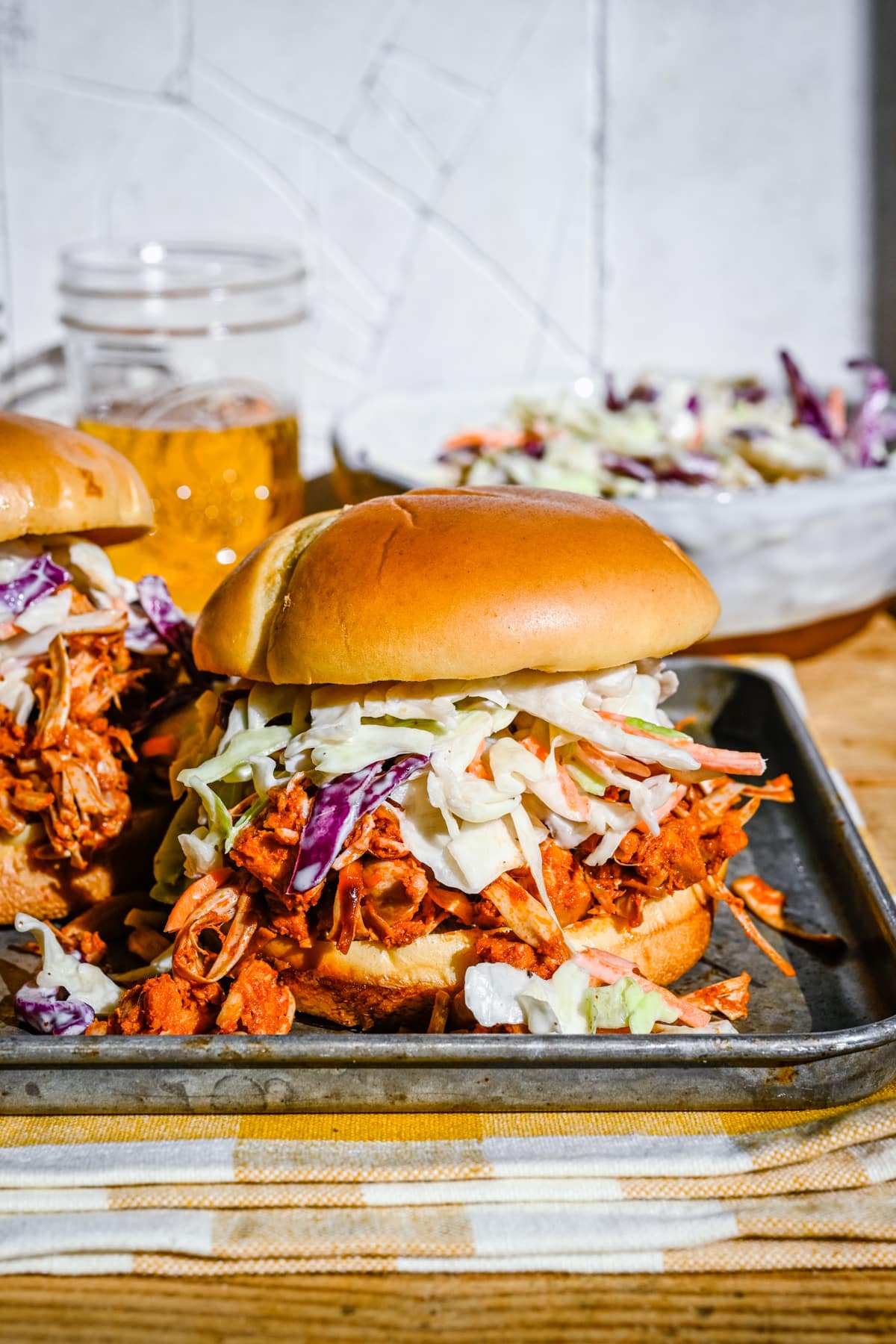 Front view of finished jackfruit burgers on a metal tray with coleslaw.