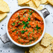 overhead view of cherry tomato salsa in a bowl with tortilla chips around it.