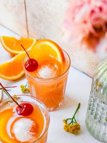 Front view of amaretto stone sour, garnished with orange and maraschino cherry.
