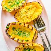 Overhead view of grilled spaghetti squash on a pink plate.