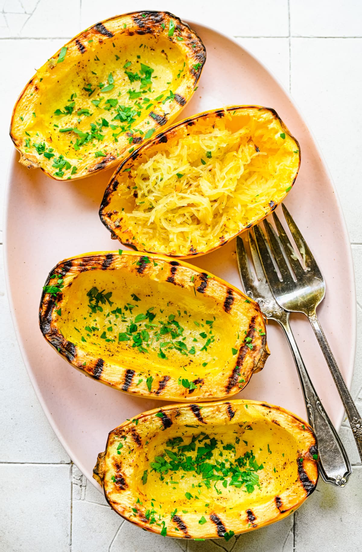 Overhead view of grilled spaghetti squash on a pink plate.