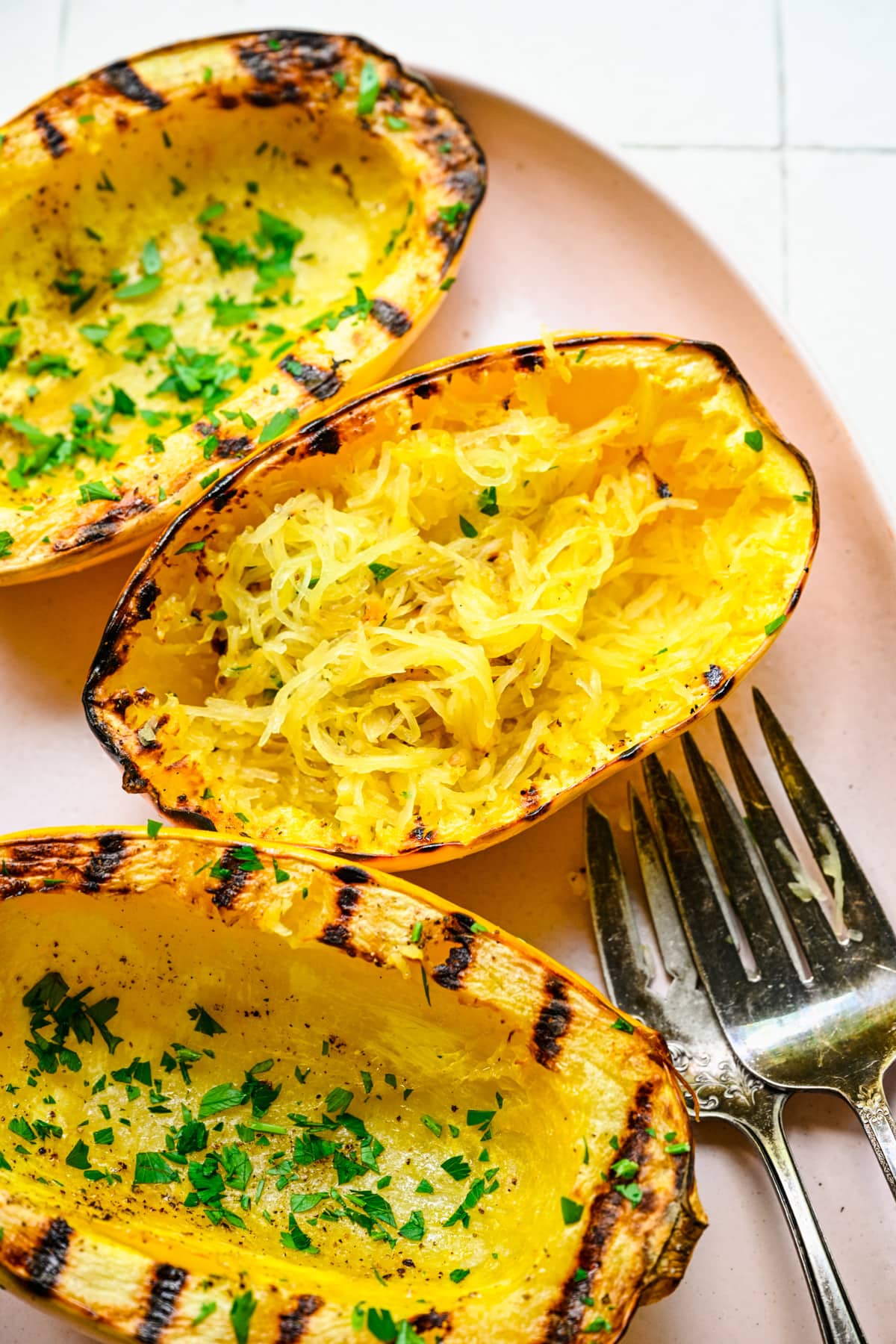 Overhead view of finished spaghetti squash on a pink platter.