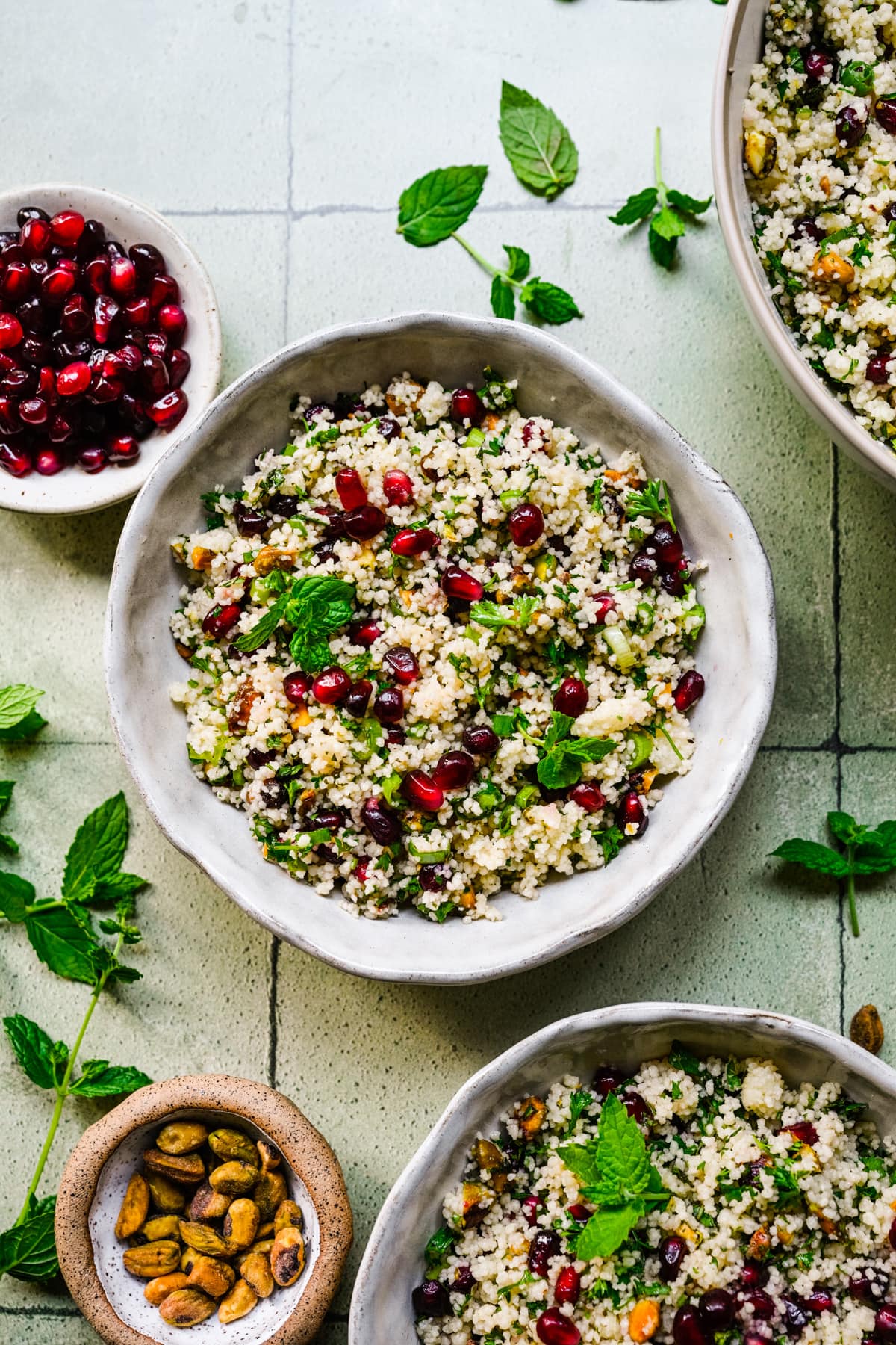 Finished couscous in two small white bowls with ingredients on the side.