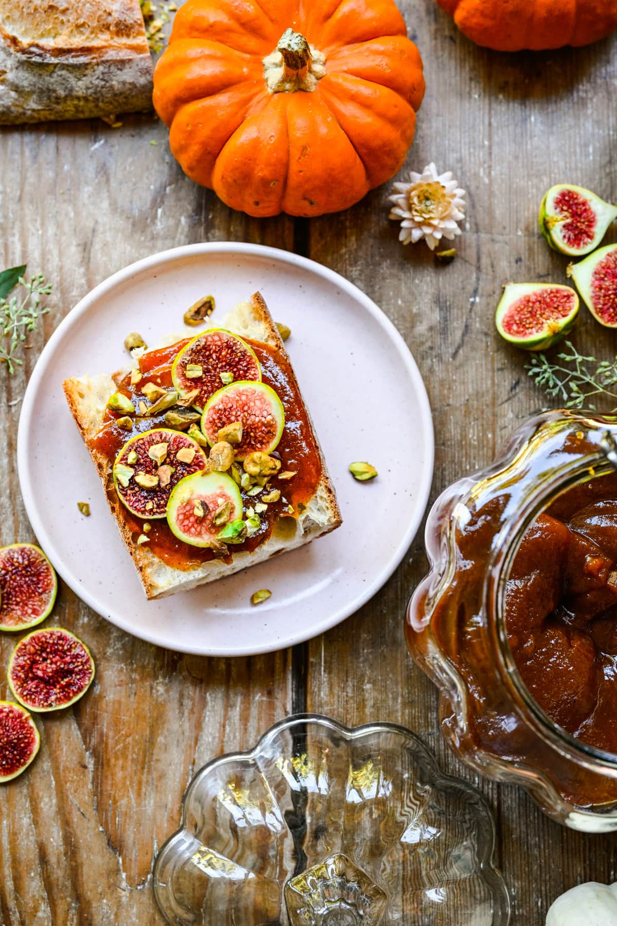 Pumpkin butter on a piece of bread with fall set up.