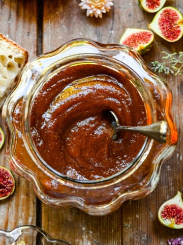 Overhead of pumpkin butter in a glass pumpkin with a spoon.