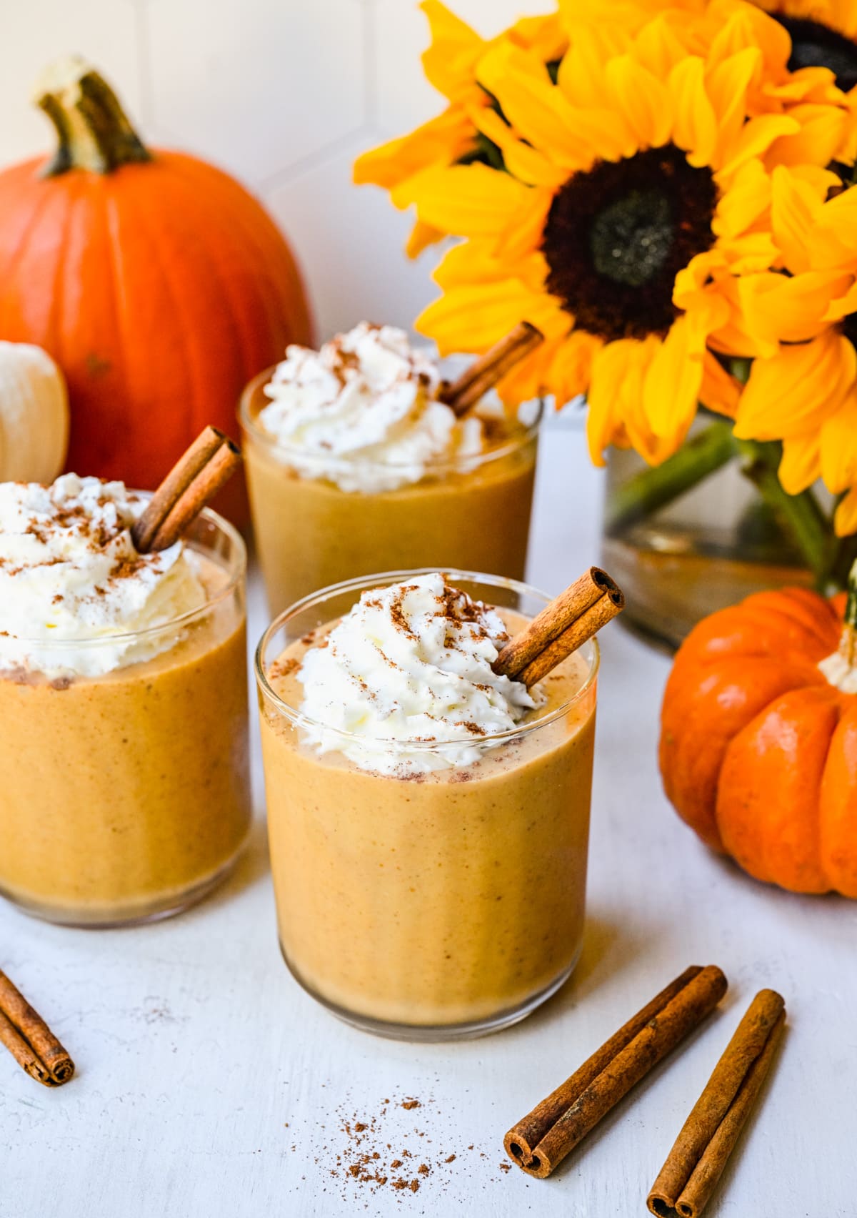 Finished pumpkin pie smoothies with whipped cream and cinnamon sticks.