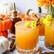 Close up view of a pumpkin spice margarita with pumpkins surrounding it.