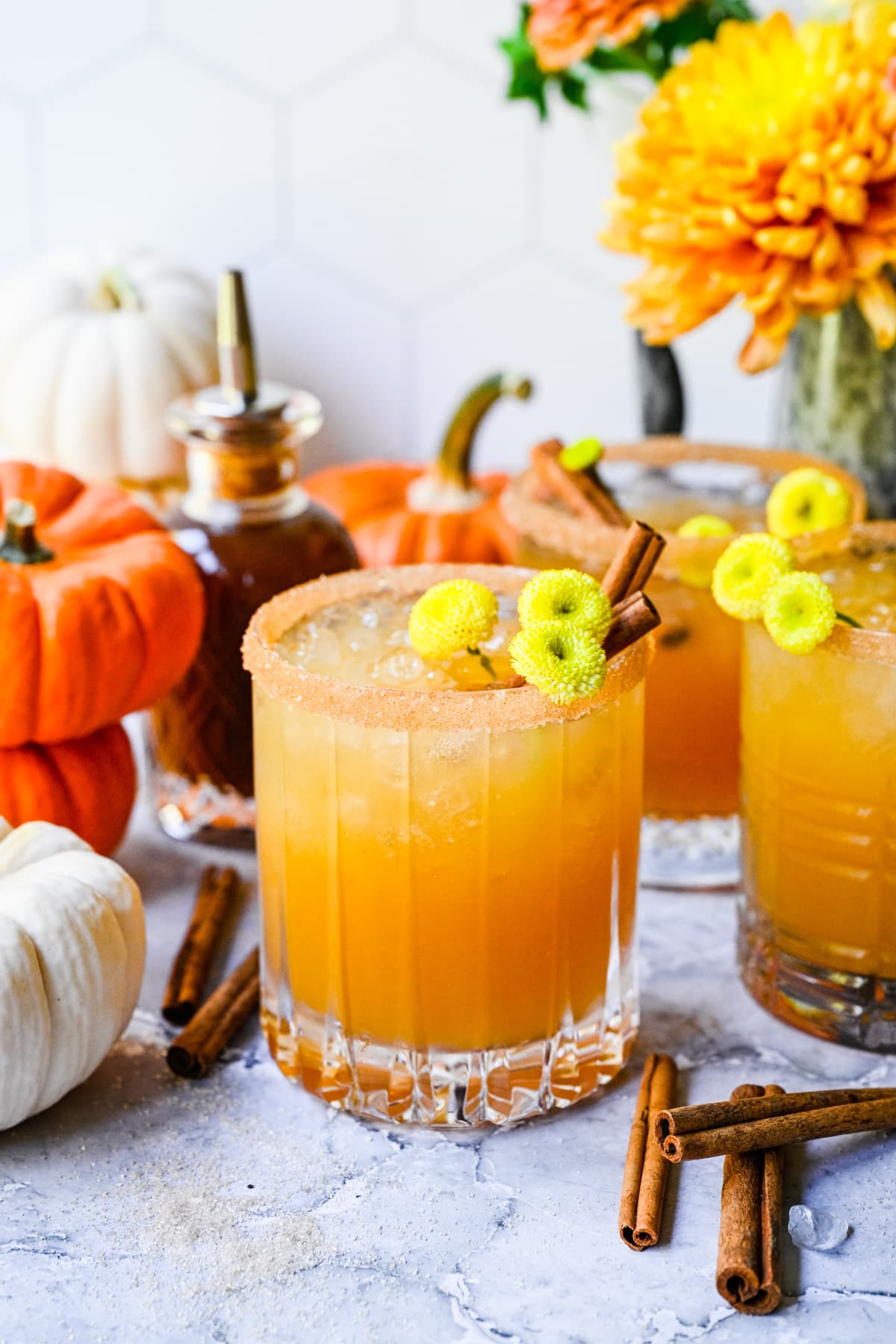 Close up view of a pumpkin spice margarita with pumpkins surrounding it.