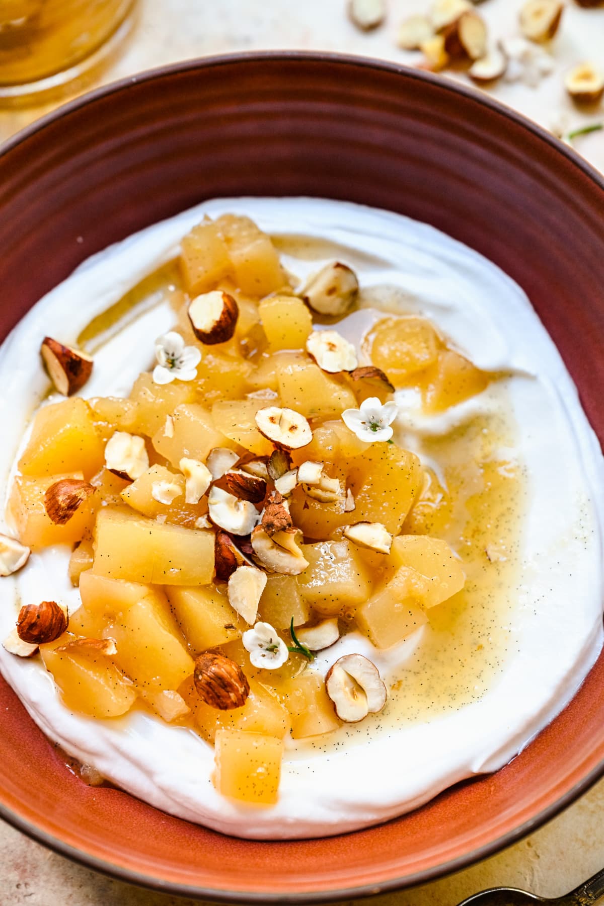 close up view of stewed pears on top of yogurt with hazelnuts.