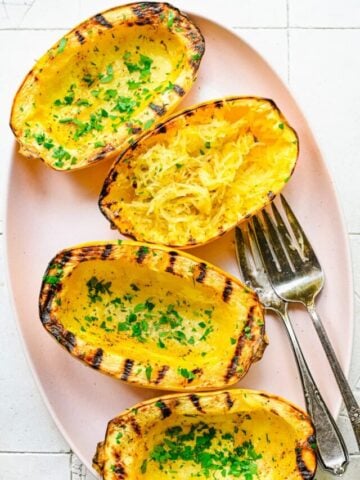 Overhead view of grilled spaghetti squash on a pink plate.