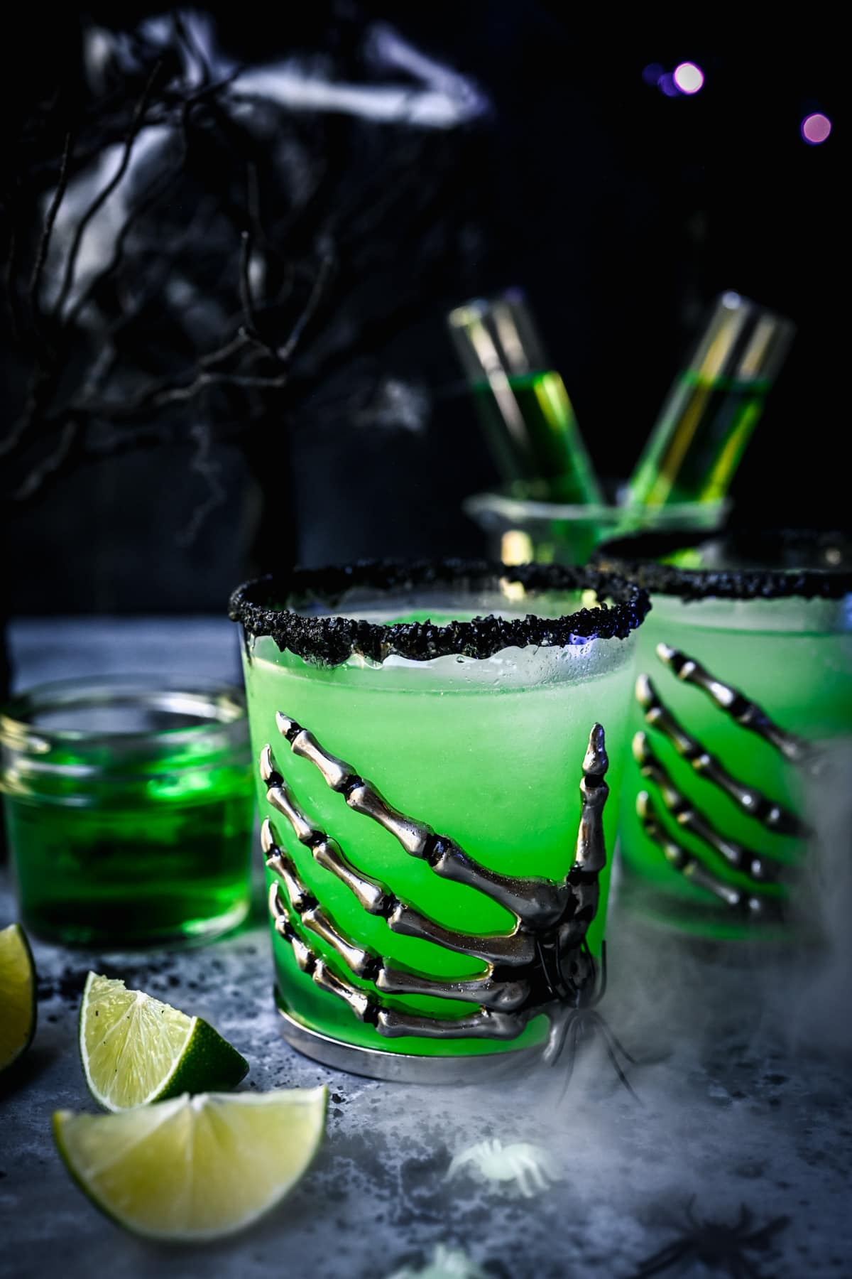 Close up view of poison apple green cocktail in skeleton hand glass.