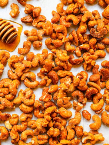 Close up of finished honey roasted cashews with honey drizzler.