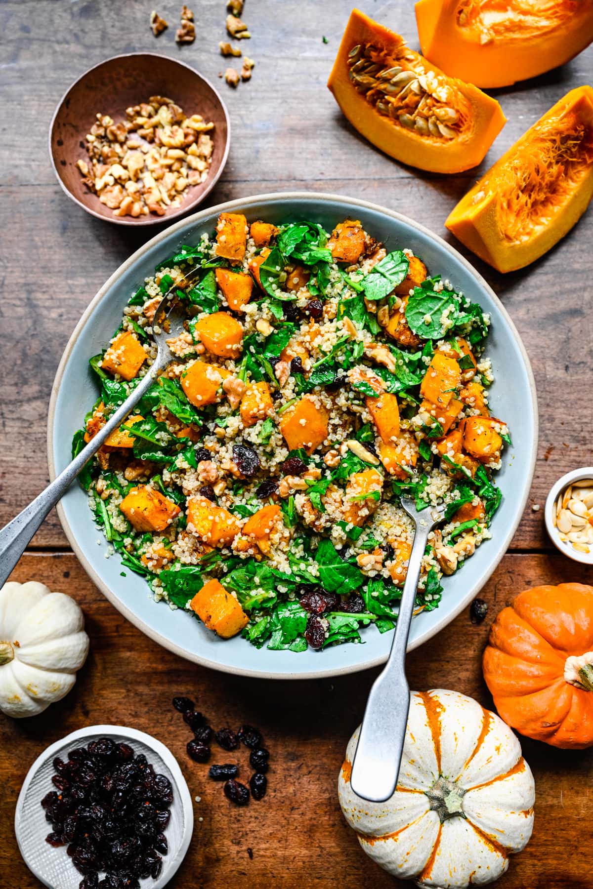 Finished pumpkin quinoa salad in a blue bowl with tongs.