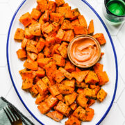 Close up of the finished roasted sweet potatoes on a white platter.