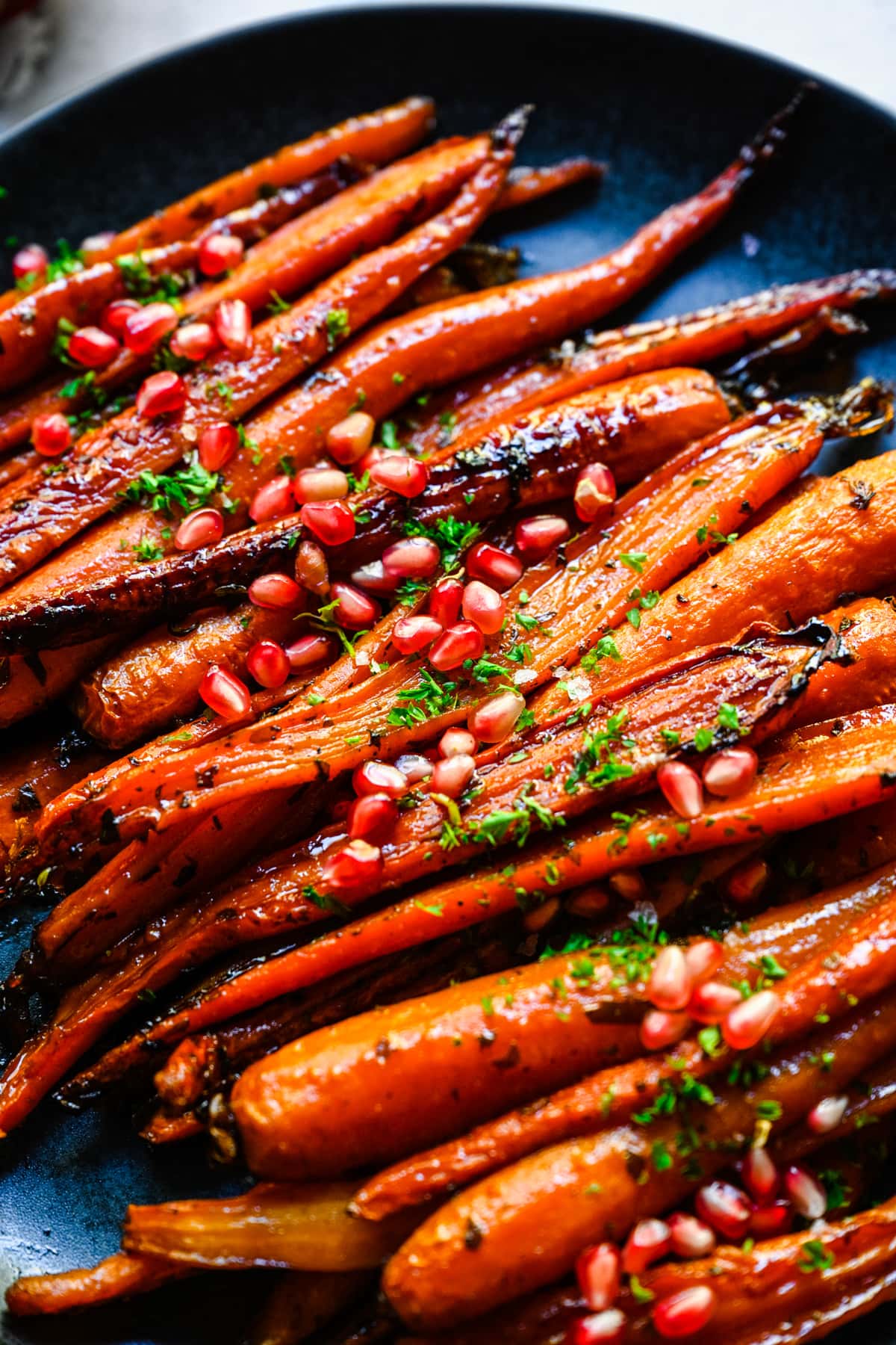 Close up view of brown sugar honey glazed carrots with pomegranate seeds.