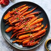 Overhead view of brown sugar honey glazed carrots on a black plate.