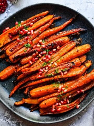 Overhead view of brown sugar honey glazed carrots on a black plate.