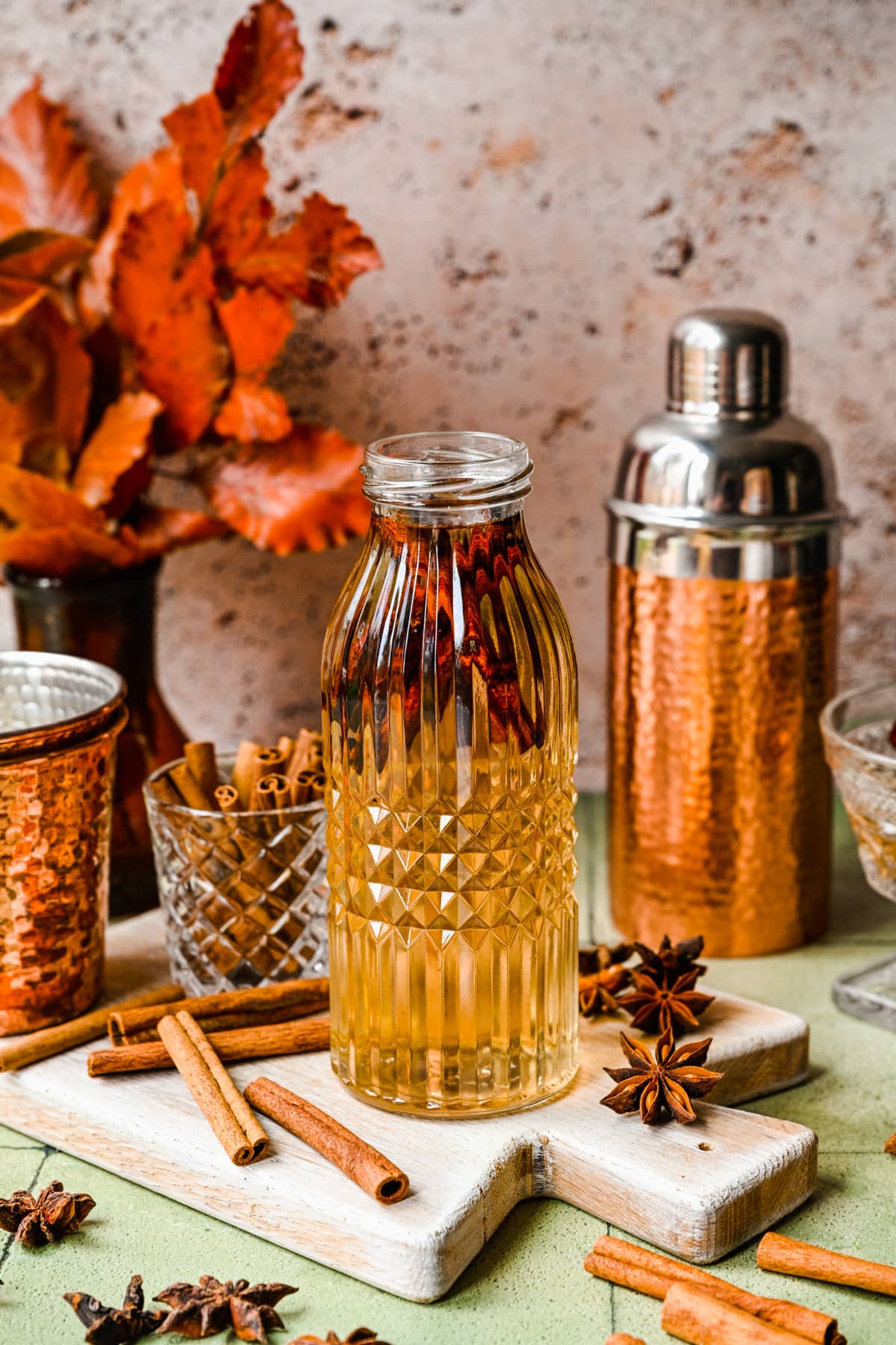 Finished cinnamon simple syrup in a glass bottle with warm colored backdrop.