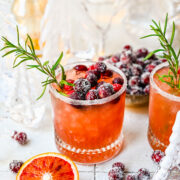 Front view of mistletoe margarita with sugared cranberries and rosemary garnish.