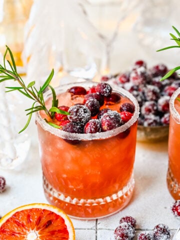 Front view of mistletoe margarita with sugared cranberries and rosemary garnish.