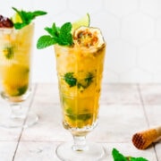 Passionfruit mojito in a tall glass with fruit and herb garnish.