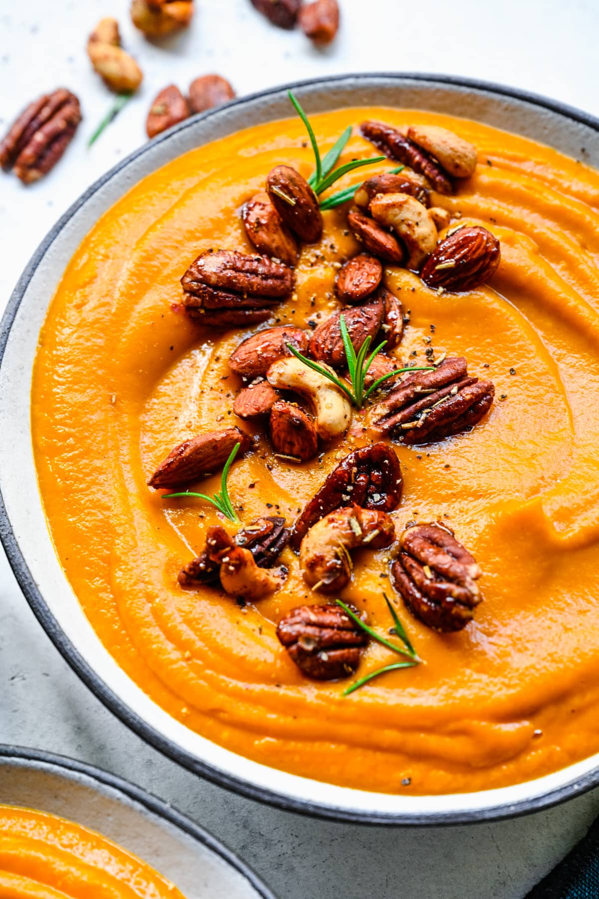 Close up of finished pumpkin sweet potato soup with nuts on top.