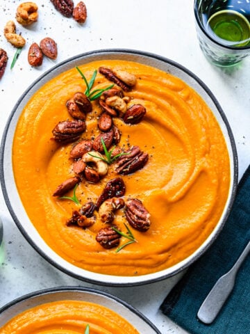 Close up of the finished pumpkin sweet potato soup in a bowl topped with nuts.