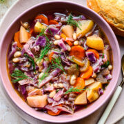 Close up of the finished red cabbage soup in a purple bowl.