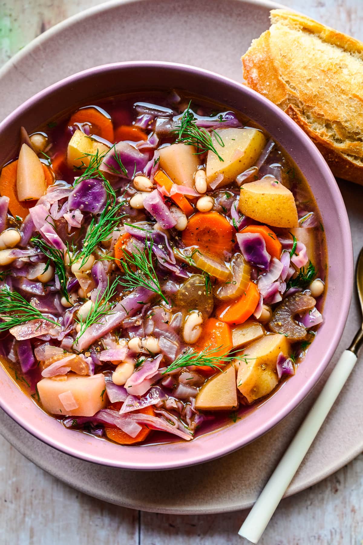 Close overhead of the finished red cabbage soup in a purple bowl.