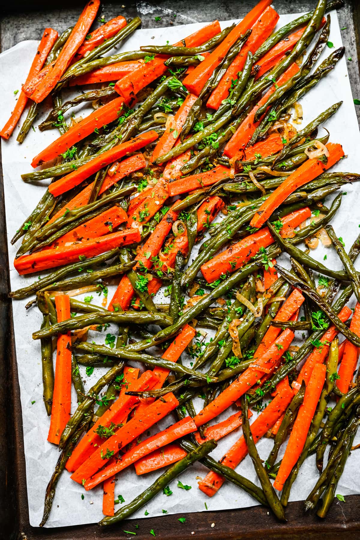 Finished roasted green beans and carrots on a sheet pan.