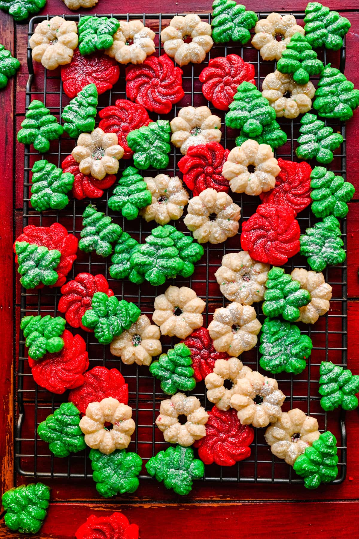 Overhead of the finished spritz cookies with a red back drop.