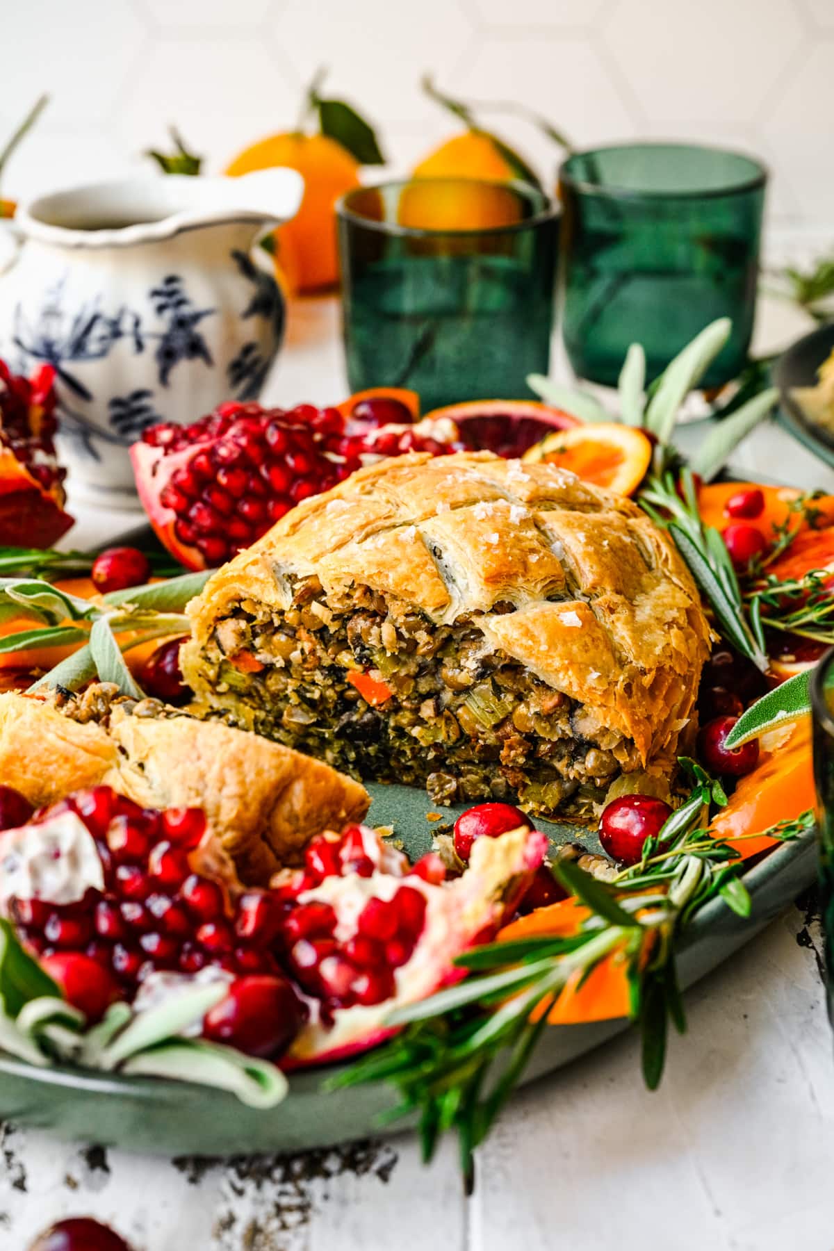 Side view of finished vegan wellington on a platter cut open with fruit and herbs.