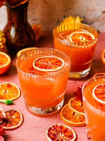 Finished blood orange old fashioned in glasses with orange garnish.