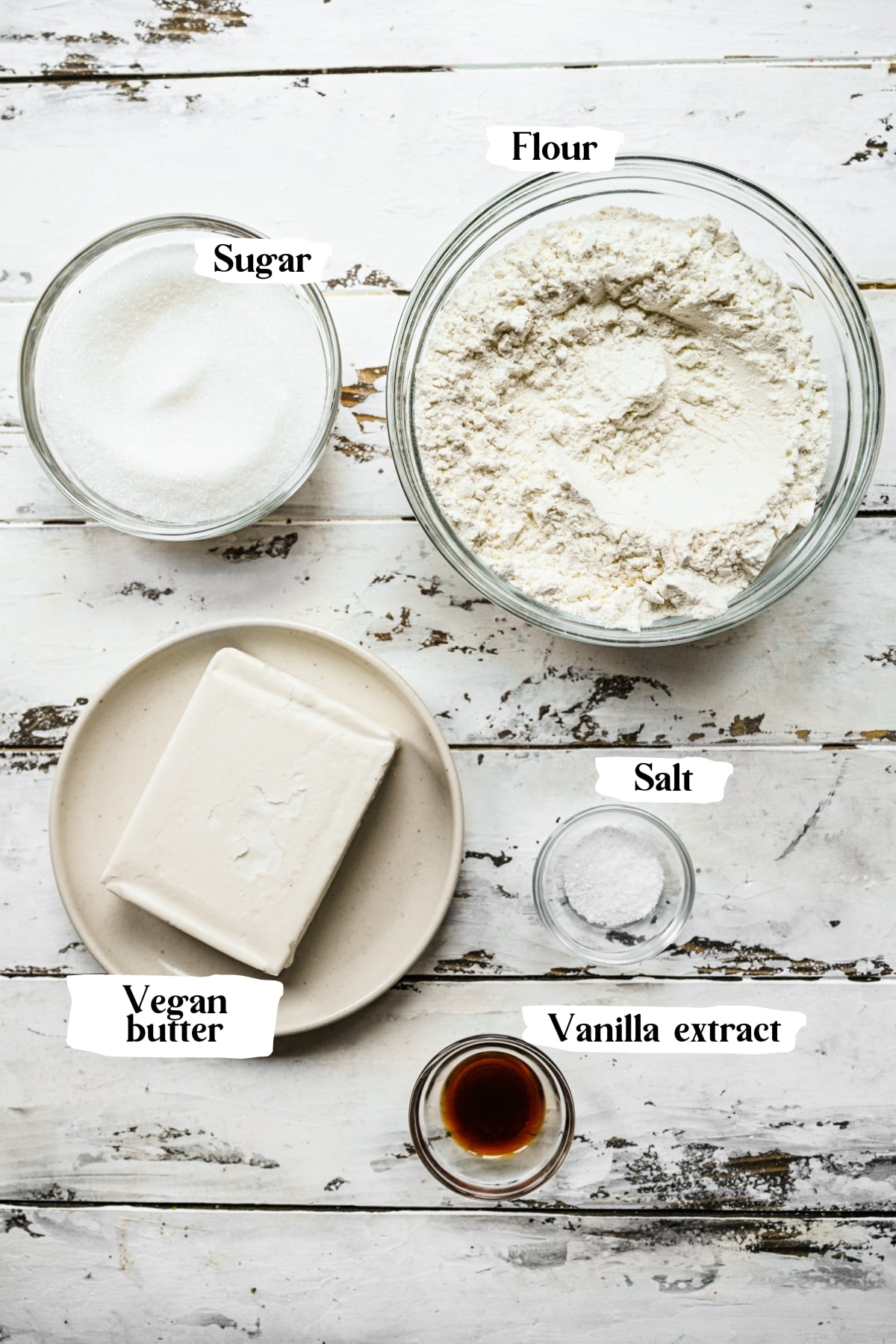 Overhead view of ingredients for vegan butter cookies, including flour, salt, sugar, butter and vanilla.