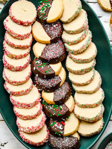 Overhead view of vegan butter cookies on a green platter with christmas ornaments.